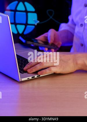 Person working on devices with digital globe and network lines in background Stock Photo
