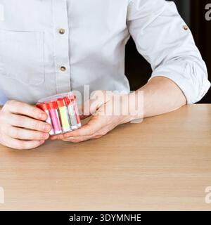 Close-up of male hands presenting round container with assorted colorful thread spools Stock Photo