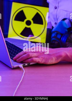 Arm extended over laptop keys with alert graphic in view, depicting potential cyber hazards. Stock Photo