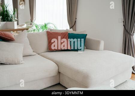 Modern living room interior with white sofa and colorful decorative pillows. Bright comfortable space with stylish minimal design. Concept of home Stock Photo