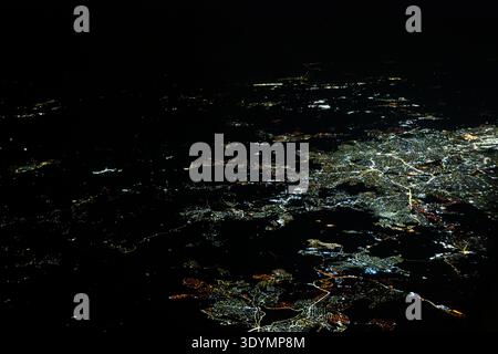 A vast network of glowing city lights spreads across the black landscape at night, resembling a complex digital web or energy infrastructure from an a Stock Photo