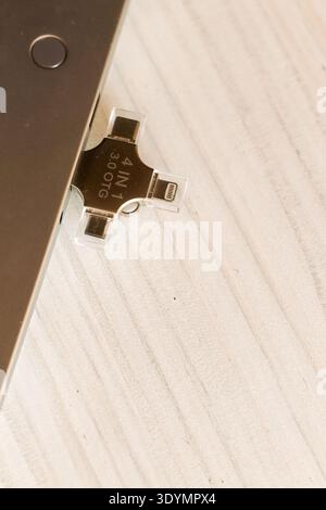 Gold 4-in-1 USB flash drive featuring multiple ports including Lightning, positioned near a laptop on a light wooden background for connectivity. Stock Photo