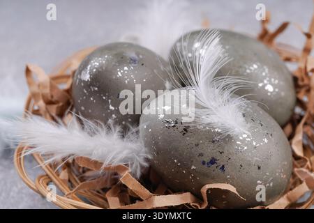 Close up Easter eggs with feathers in wicker nest Stock Photo
