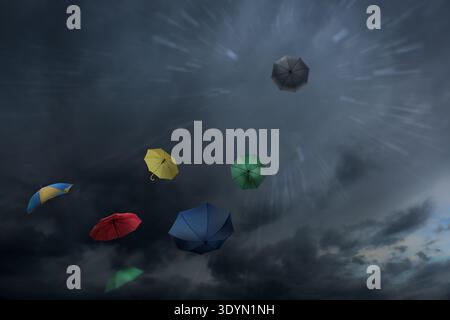 Umbrellas flying in dark cloudy sky. Stormy weather Stock Photo