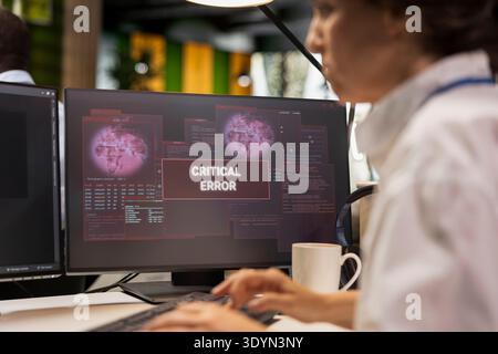 Close up of programmer at office desk thinking how to fix critical error alert displayed on PC screen. Software developer brainstorming how to fix computer bug affecting server network Stock Photo