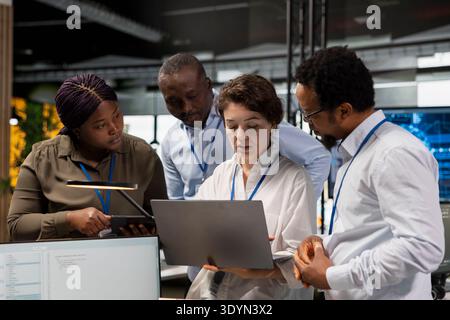 Engineering team in Silicon Valley company office developing software apps with laptop. Teamworking colleagues using notebook at work to code, debugging applications to resolve issues Stock Photo