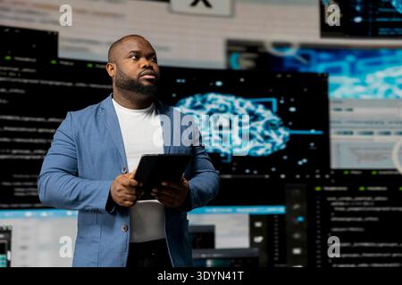 Black software expert focusing on programming language for innovation, reading binary code on terminal window. Reviews code development for data science. Modern futuristic coding life. Stock Photo