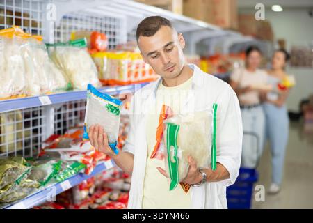 Pensive shopper choosing Asian noodles at grocery store Stock Photo
