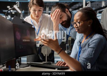 Upset data center workers unnerved by spyware detecting by cybersecurity systems. Disturbed Server hub IT professionals trying to repair malicious threats security breaches Stock Photo