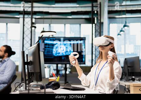 Female engineer using virtual reality tech adjusting deep learning algorithms parameters to automate tasks. Intern wearing VR headset working with AI driven insights on notebook for code optimization Stock Photo