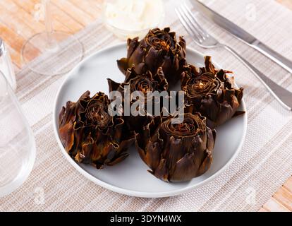 Tasty whole roasted artichokes served on plate Stock Photo