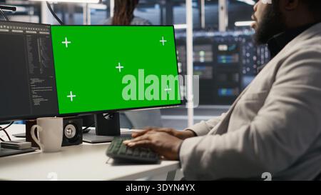 Data center admin using isolated screen PC to monitor neural network AI. Server room employee using mockup computer to oversee rigs powering machine learning processes, camera A Stock Photo