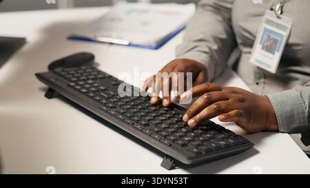 Close up of data center admin coding on PC, doing software updates for AI mainframes. Server farm IT professional typing on computer keyboard, optimizing infrastructure, camera A Stock Photo