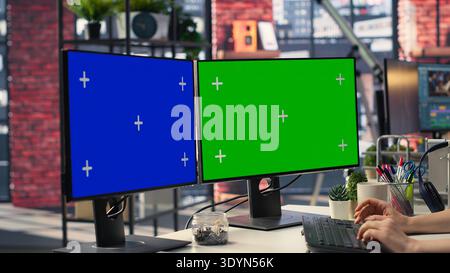 Businesswoman in a modern workplace types on a keyboard next to chroma key, using a creative agency office setup for digital media work. High tech workstation perfect for tasks. Camera A. Stock Photo