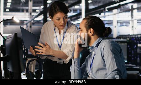 Data center admins working together, collaborating on neural network software development. Teamworking server hub colleagues implementing artificial intelligence technology in workplace, camera A Stock Photo