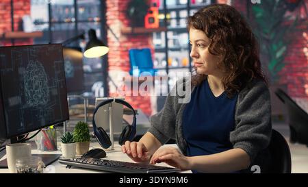 Teleworking developer using computer for artificial intelligence computing through self learning algorithms. Agency IT engineer works with AI deep neural networks on desktop PC. Camera B. Stock Photo