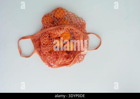 Oranges in a net bag on a light background Stock Photo
