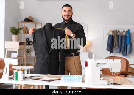 Male tailor measuring jacket on mannequin in atelier Stock Photo