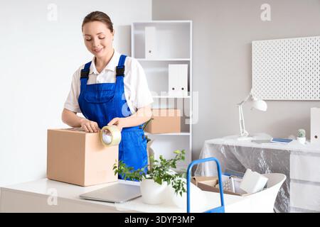 Female worker taping box in office on moving day Stock Photo