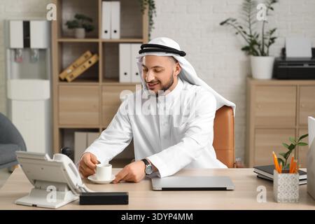 Arab businessman with cup of coffee at table in office Stock Photo