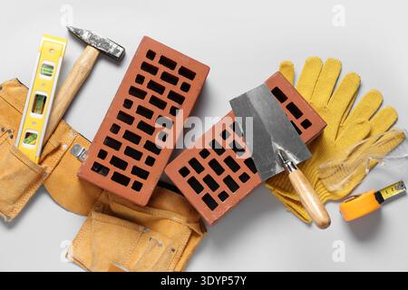 Bricks with builder belt and different tools on white background Stock Photo