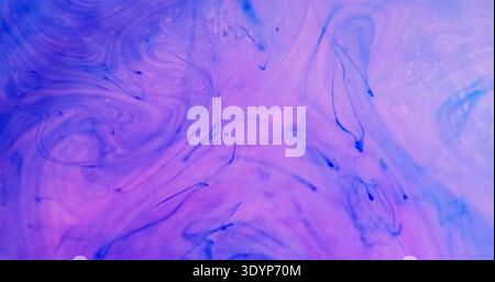 Color ink splash. Acrylic water. Blur purple blue droplet fog bright liquid pigment spill texture spreading on abstract background. Stock Photo