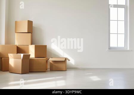 Cardboard Boxes Stacked in Bright Empty Room Near Window Stock Photo