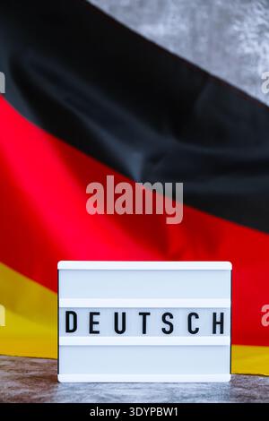 Lightbox with text DEUTSCH National symbol of Germany. German wave silky flag background. Concept of education and learning languages  Stock Photo