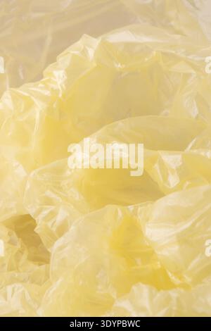 Crumpled yellow plastic creating an abstract background texture. Showing wrinkles, folds, and highlights on transparent polyethylene material Stock Photo