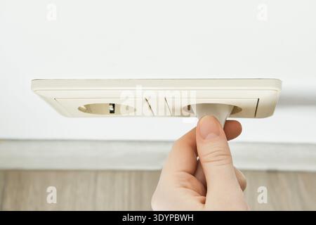 Hand inserting an electric plug into an electrical outlet for energy Stock Photo