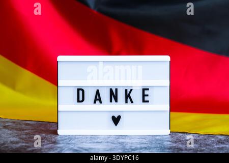 Lightbox with text DANKE THANK YOU National symbol of Germany. German wave silky flag background. Concept of thanksgiving day and gratitude  Stock Photo