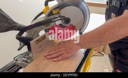 Worker Using Miter Saw to Cut Wood Plank Stock Photo