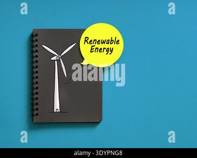 Black notebook with a hand drawn wind turbine and a yellow speech bubble showing Renewable Energy text, on a blue background Stock Photo