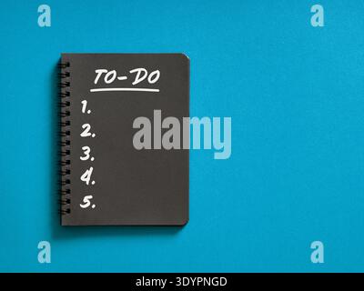 Black spiral notebook displaying a handwritten to do list with numbered items, symbolizing planning, productivity, and task management Stock Photo