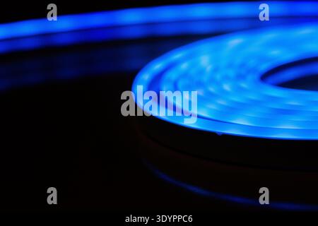 Blue LED light strip glowing in spiral on dark background Stock Photo