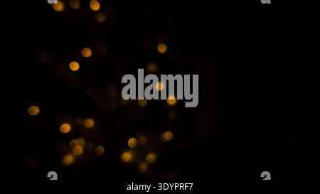 Light bokeh glowing as warm golden circles scattered across dark background. Light creating soft abstract sparkle pattern with defocused illumination, Stock Photo