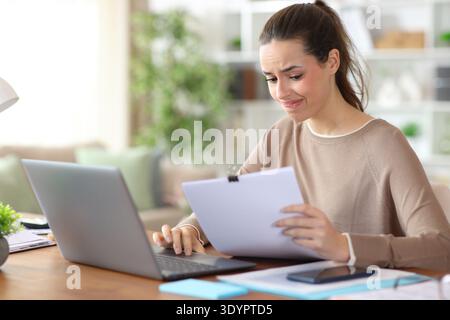 Worried freelance worker reading paper documents working online at home Stock Photo