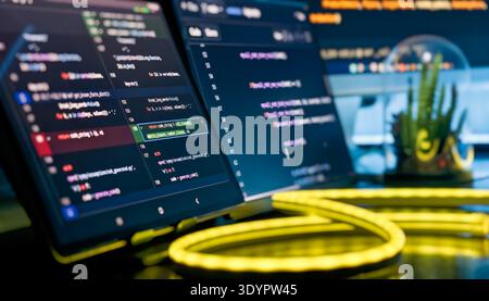 Close-Up Code Editor Screen with Neon Yellow Cable Light and Modern Developer Workspace Stock Photo