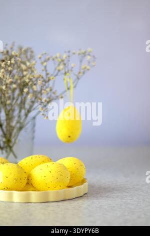 Yellow Easter egg decoration with speckled eggs on a plate and soft spring flowers Stock Photo