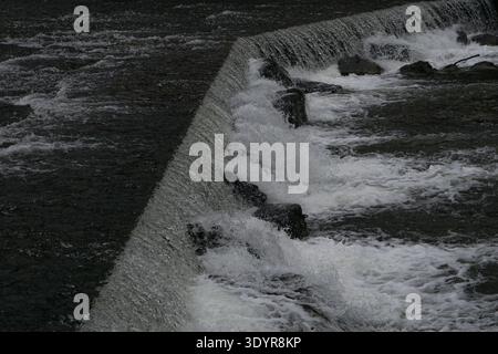 Water flowing over a small weir in the old industrial canal of the Sihl River in Zurich-Leimbach, Switzerland. Stock Photo