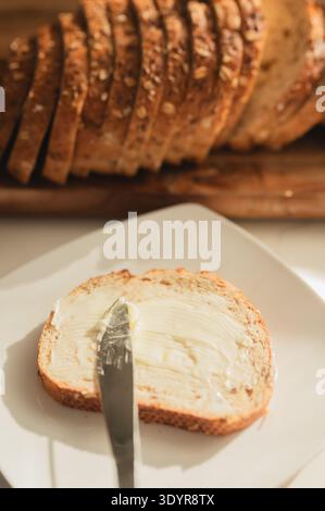 Butter knife spreading grass-fed butter on sourdough toast slice Stock Photo