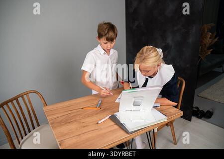 Children Schoolwork Homework - Boy and girl doing homework together at a table in a room. Stock Photo