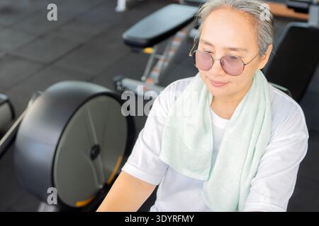 High angle view of an attractive mature Asian woman exercising in gym. Retirement healthy and fitness lifestyle and concept Stock Photo