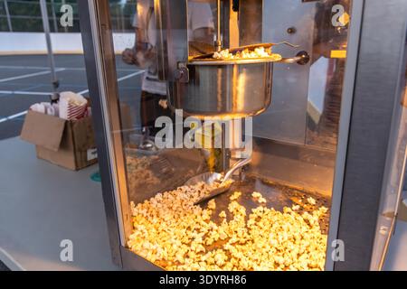 Freshly popped popcorn is being made in a popcorn machine at a sporting event, ready to be enjoyed by spectators Stock Photo