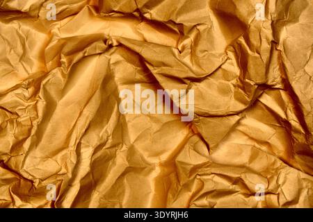 Crumpled brown gold paper texture background with heavy creases and wrinkled folds Stock Photo