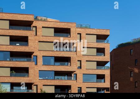 View of warm brick buildings rising against a crisp blue sky, balconies hinting at urban life in the modern architecture, Oslo, Oslo, Norway. Stock Photo