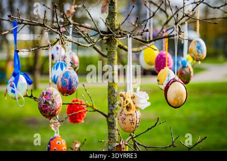 Decorative hand-painted Easter eggs hanging from tree branches in a public park during spring festivities in Druskininkai, Lithuania. Stock Photo