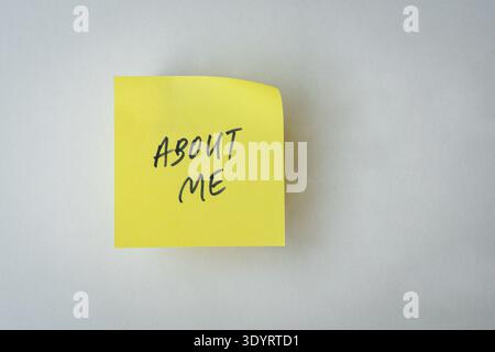 About Me note or message on yellow paper. Isolated on white surface. Stock Photo