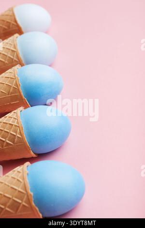 Blue easter eggs in waffle cones on pink background Stock Photo