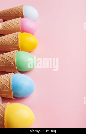 Colorful easter eggs in waffle cones on pink background Stock Photo